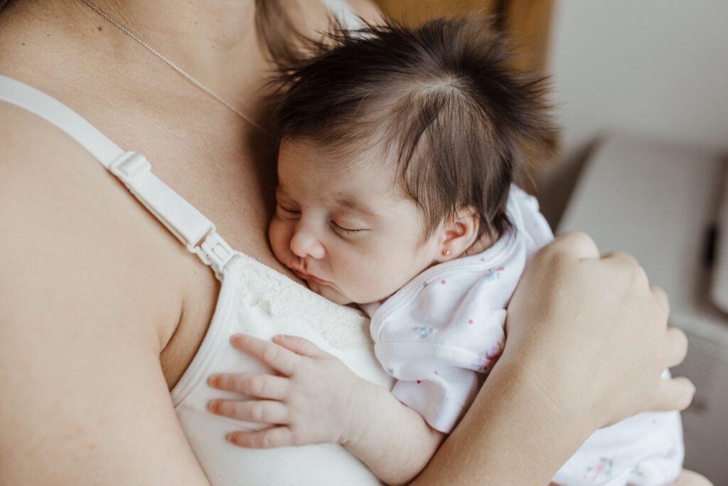 Mae exausta chorando na madrugada com o bebe lidando com a privacao de sono na maternidade.